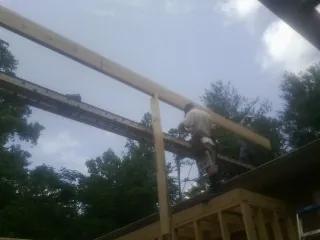 Carpenter setting a ridge beam over a new addition frame — Ice Dam Removal by Roofing Brothers in Blockton