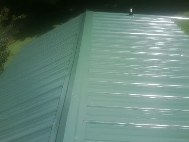 New green metal panels meeting at the ridge of a roof — Flat Roof Repair work by our crew in Blockton