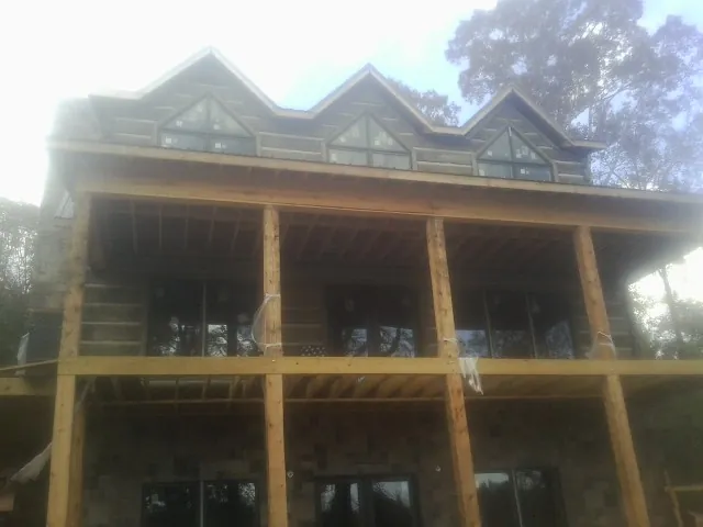 Dormers and porch framing on a large log home under construction — Roof Coating work by our crew in Blockton