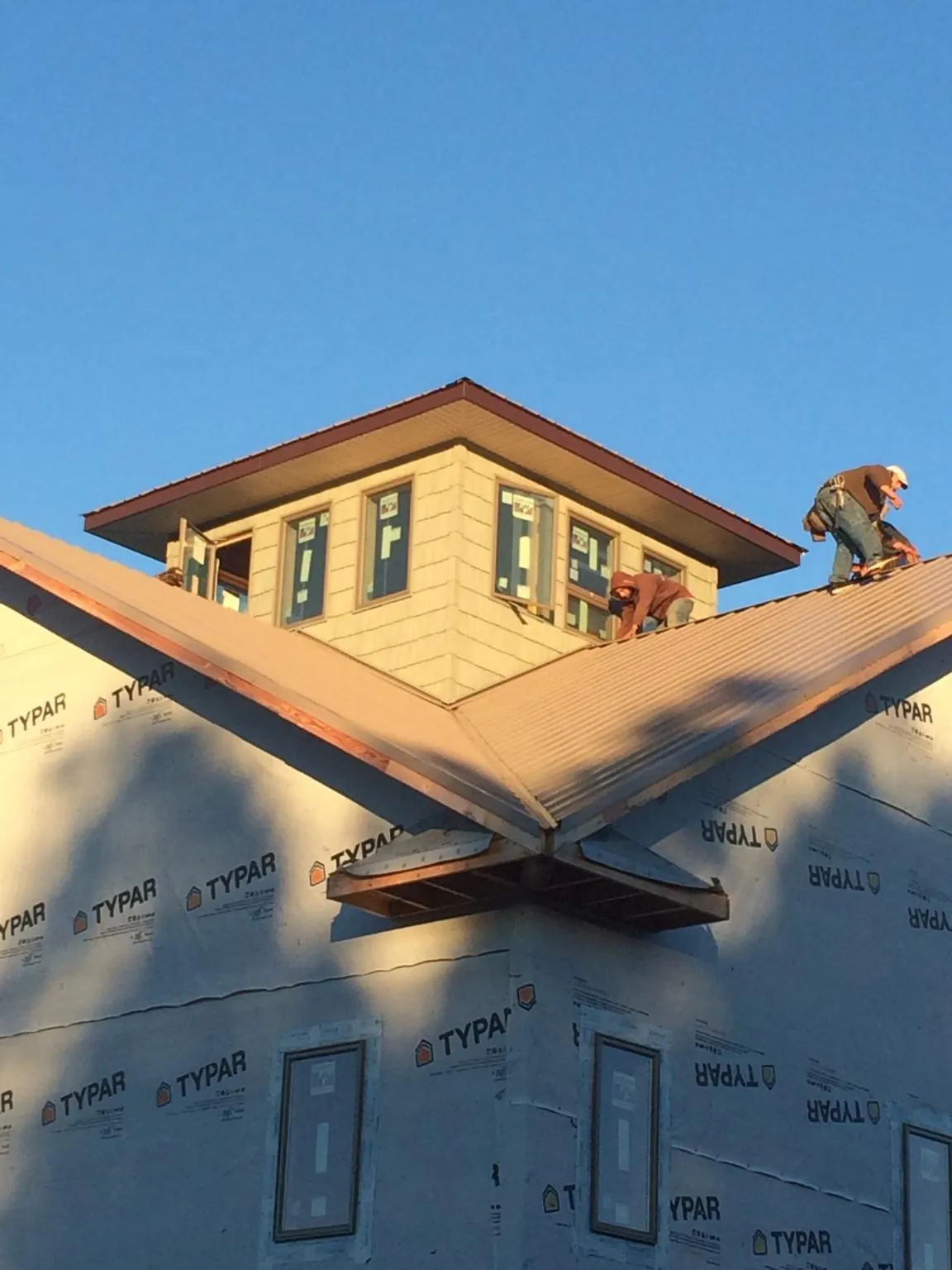 Roofers working around a rooftop cupola on a new metal roof at sunset — Roof Waterproofing in Blockton by Roofing Brothers